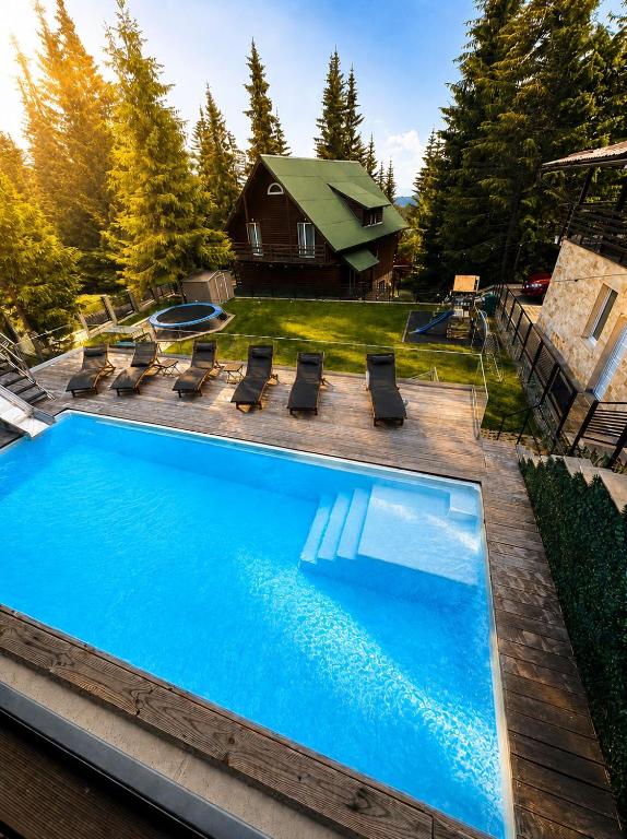 a swimming pool with chairs and a house at Transylvania Villa & Spa in Muntele Băişorii