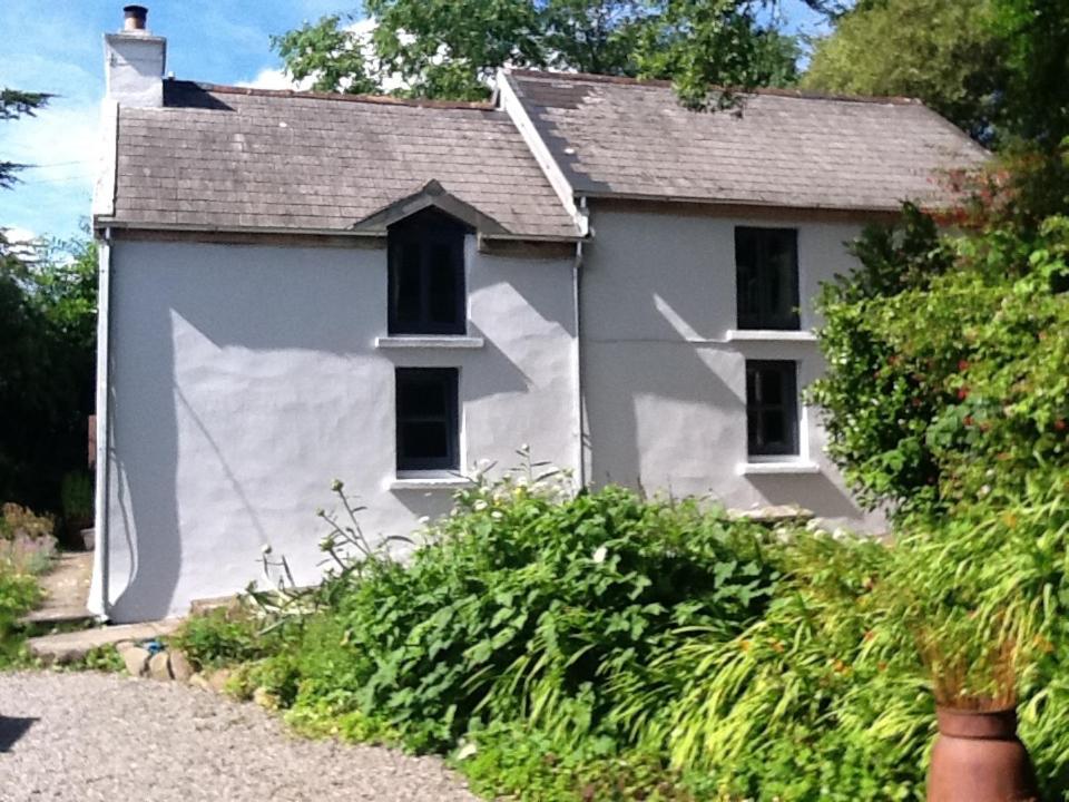 a white house with a window and some bushes at Shiplake Mountain Farmhouse in Dunmanway