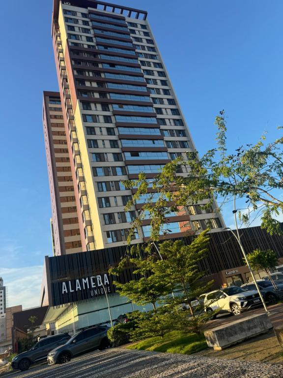 a tall building with cars parked in front of it at Flat no bairro universitário in Caruaru
