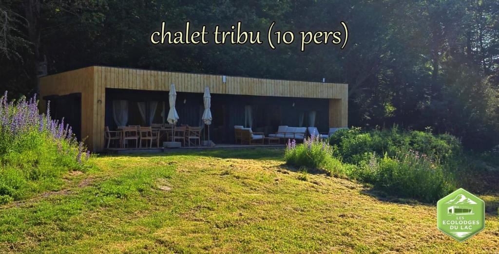 a building with tables and umbrellas in a yard at Les Ecolodges du Lac in Chambon-sur-Lac