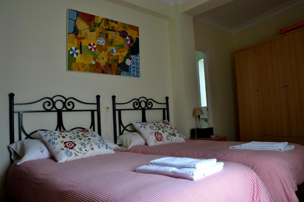 Pension Bajamar في Ladrido: غرفة نوم بسريرين عليها مناشف