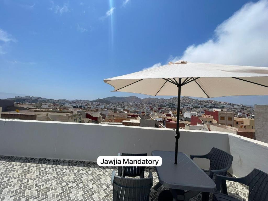 a table and chairs under an umbrella on a roof at Alhoceima Appartement Loft with PANORAMIC view in Al Hoceïma