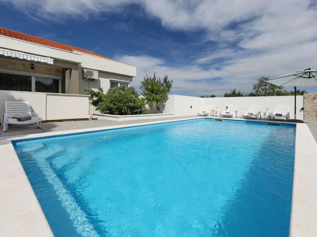 a swimming pool with blue water in front of a house at Holiday Home Karlo by Interhome in Posedarje