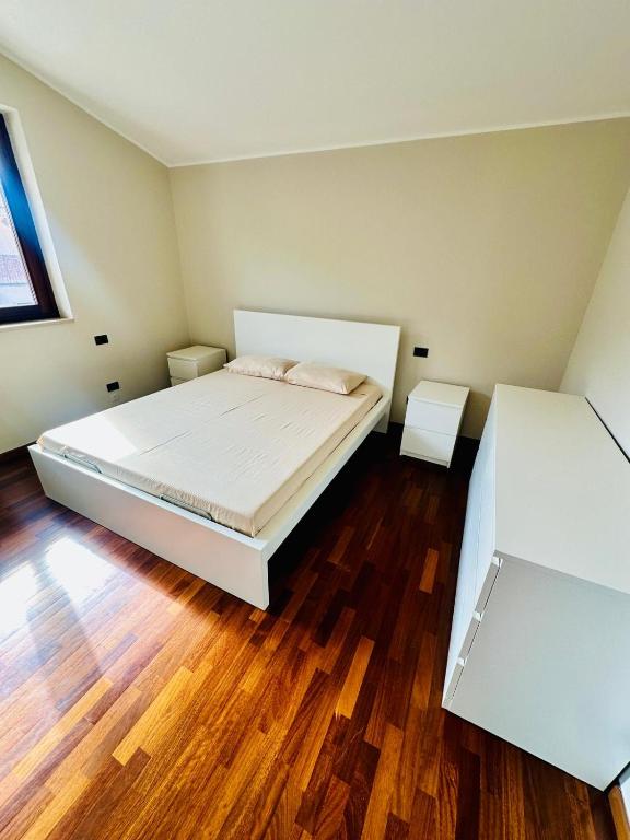 a bedroom with two white beds and wooden floors at Intero appartamento a pochi passi dalla piazza in Marostica