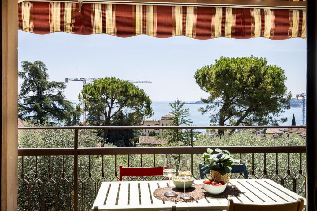 a balcony with a table and a view of the water at Latte & Menta by Garda FeWo in Gardone Riviera