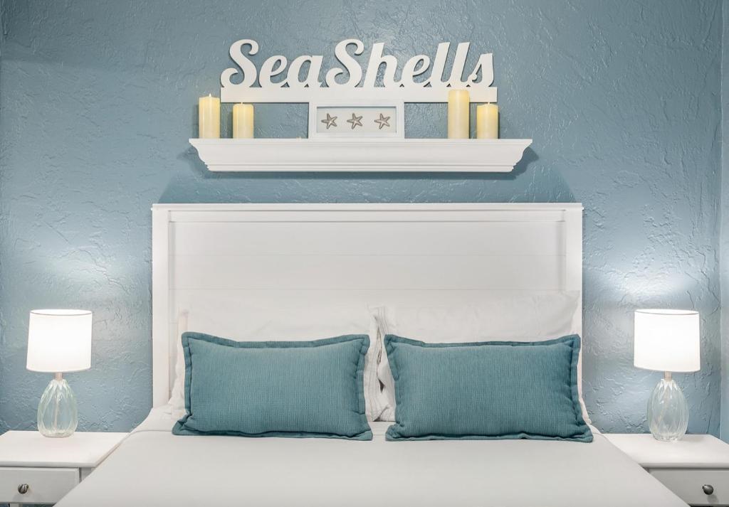 ein Bett mit weißem Kopfteil und einem darüberliegenden Regal in der Unterkunft Seashells Getaway - Boat Slip, Ramp, Pool in Marathon