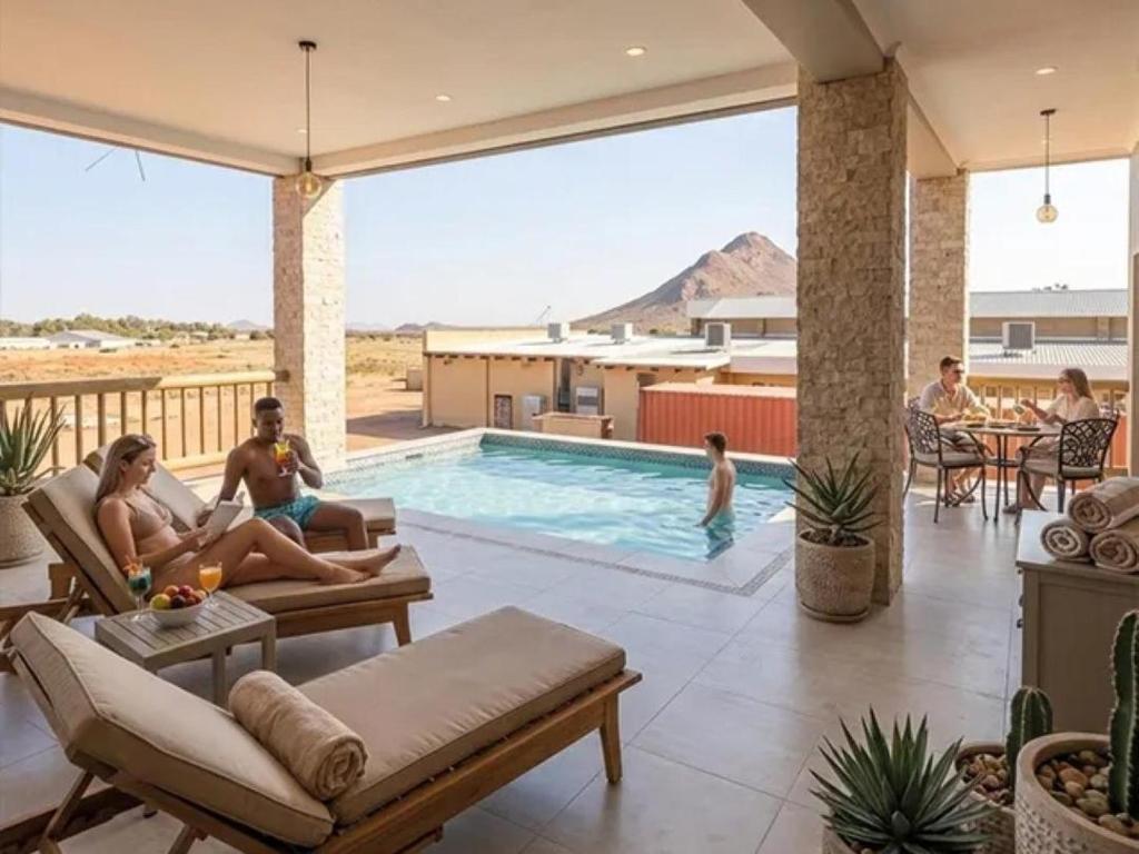 a group of people sitting around a swimming pool at Aggeneys Hotel in Aggeneys