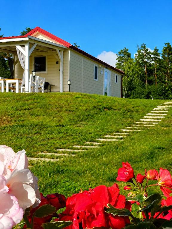 a house with steps leading to a yard with red flowers at Osada Wilaneska domki Mikołajki Mazury in Mikołajki