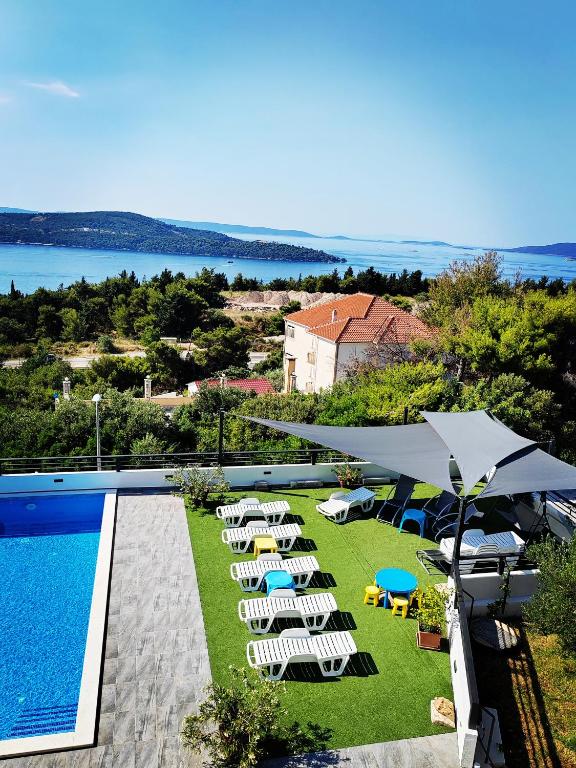 a pool with chairs and umbrellas next to a resort at Villa Confido - Luxury 3BR Apartment with Private Pool near Trogir in Donji Seget