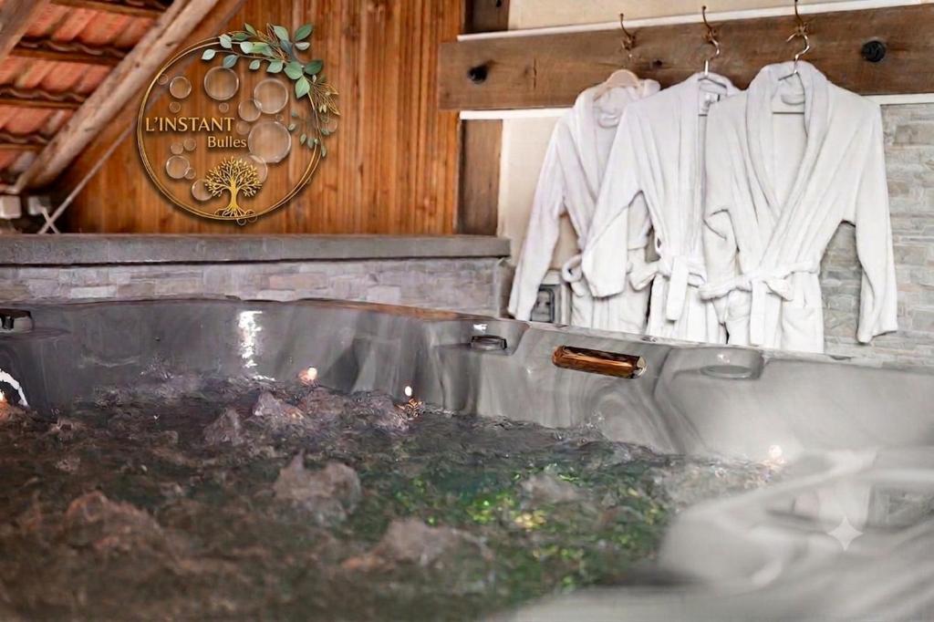 a bathroom with a bath tub and clothes hanging on a wall at Maison d'hôtes avec Jacuzzi -Sauna in Montreux-Château