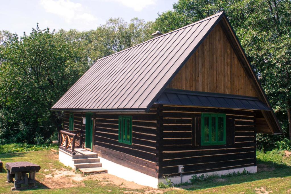a log cabin with a metal roof and green windows at Chata U3G Kobyly-Mlynky in Kobyly