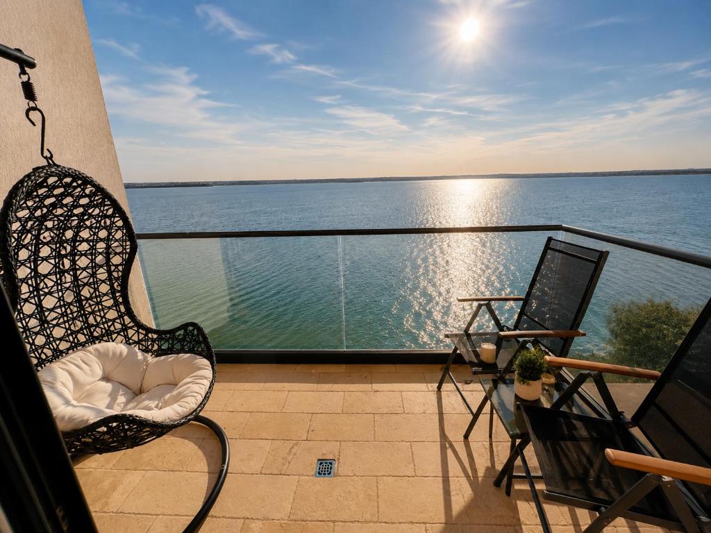 a balcony with a chair and a view of the water at SOPHIA LAKE VIEW SUITE in Mamaia