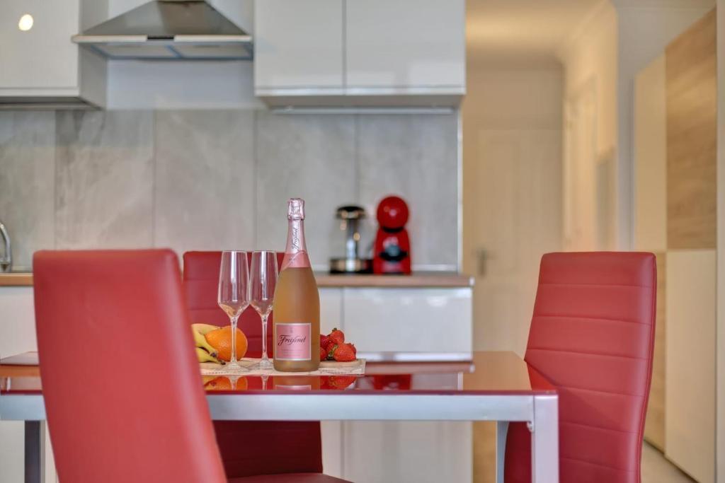a table with a bottle of wine and two red chairs at GOLF Villa233 in San Miguel de Abona
