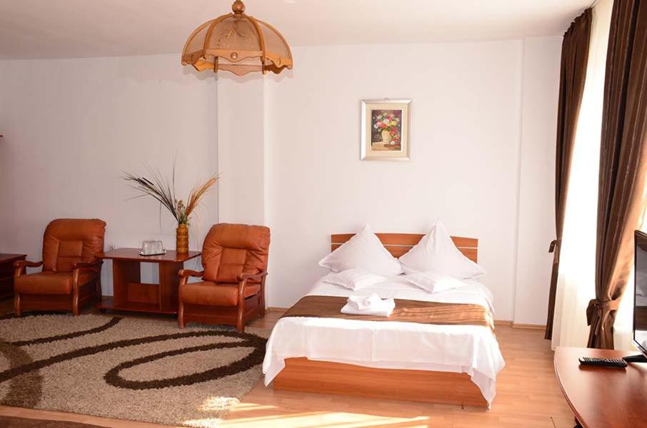 a bedroom with a bed and a table and chairs at Hotel Delaf in Cluj-Napoca