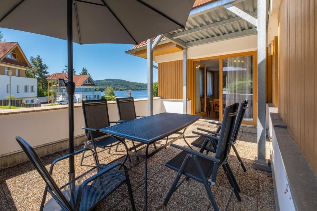 a table and chairs on a balcony with an umbrella at Apartment Riviera 503-8 Lipno Home in Lipno nad Vltavou