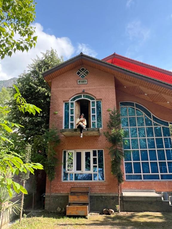 a person sitting in the window of a house at Urban Den Hostel in Srinagar