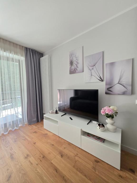 a living room with a television on a white cabinet at Kurzemes Pērle Beach Apartament - Albatross in Ķesterciems