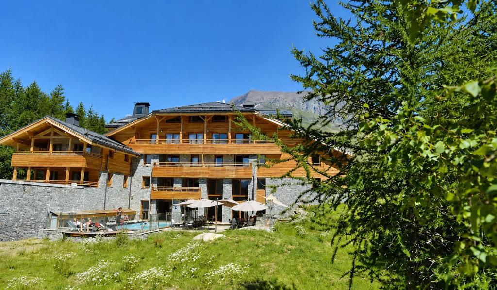 a large wooden building with umbrellas in front of it at Alpenrose Alpe d'Huez in LʼHuez