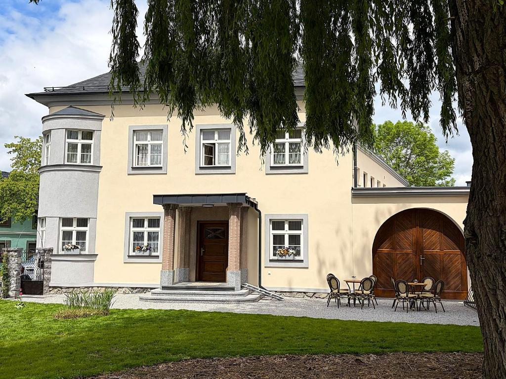 a large yellow house with chairs in front of it at Penzion Hněvotín 88 in Hněvotín