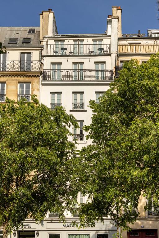 a tall white building with trees in front of it at Hôtel Marais Hôme in Paris
