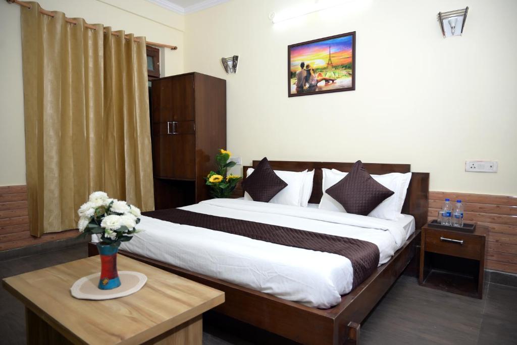 a bedroom with a bed and a vase of flowers on a table at Hotel King By Panch Aarohan in Pithorāgarh