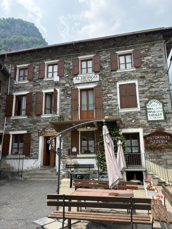 a building with a bench and an umbrella in front of it at Albergo Nonaj in Monticello d'Alba