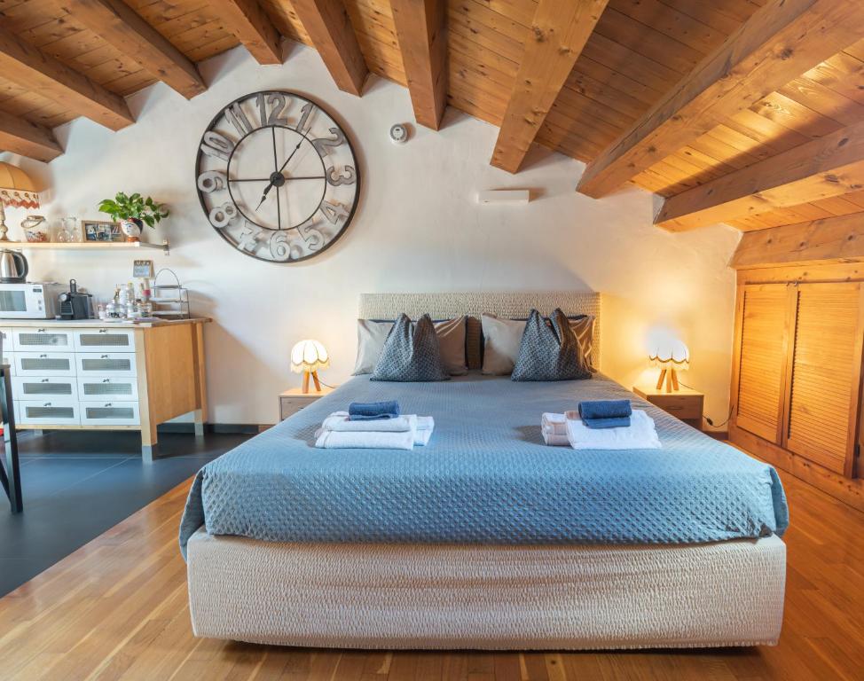 ein Schlafzimmer mit einem großen Bett und einer Uhr an der Wand in der Unterkunft Torre Cà Emo, La Mansarda dell'Ammiraglio in Vittorio Veneto