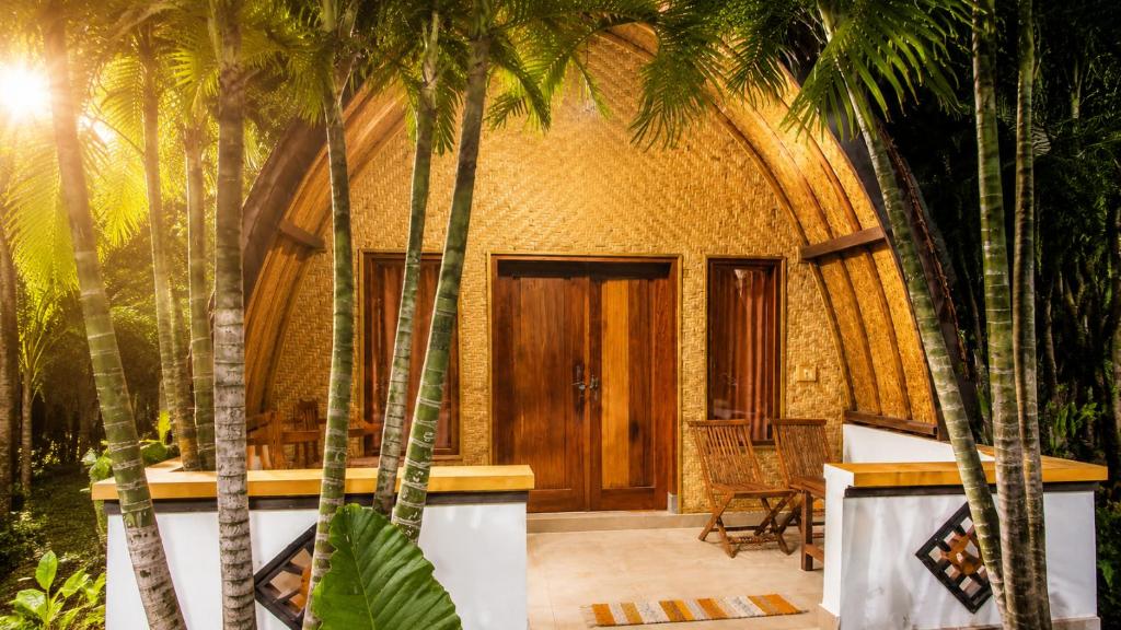 a house with palm trees in front of it at Warna Cottage in Gili Trawangan