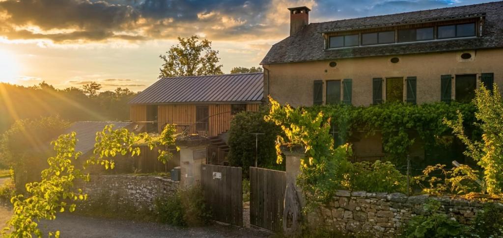 a house with the sun setting behind it at Chez Walter et Camille in Saint-Cernin-de-Larche