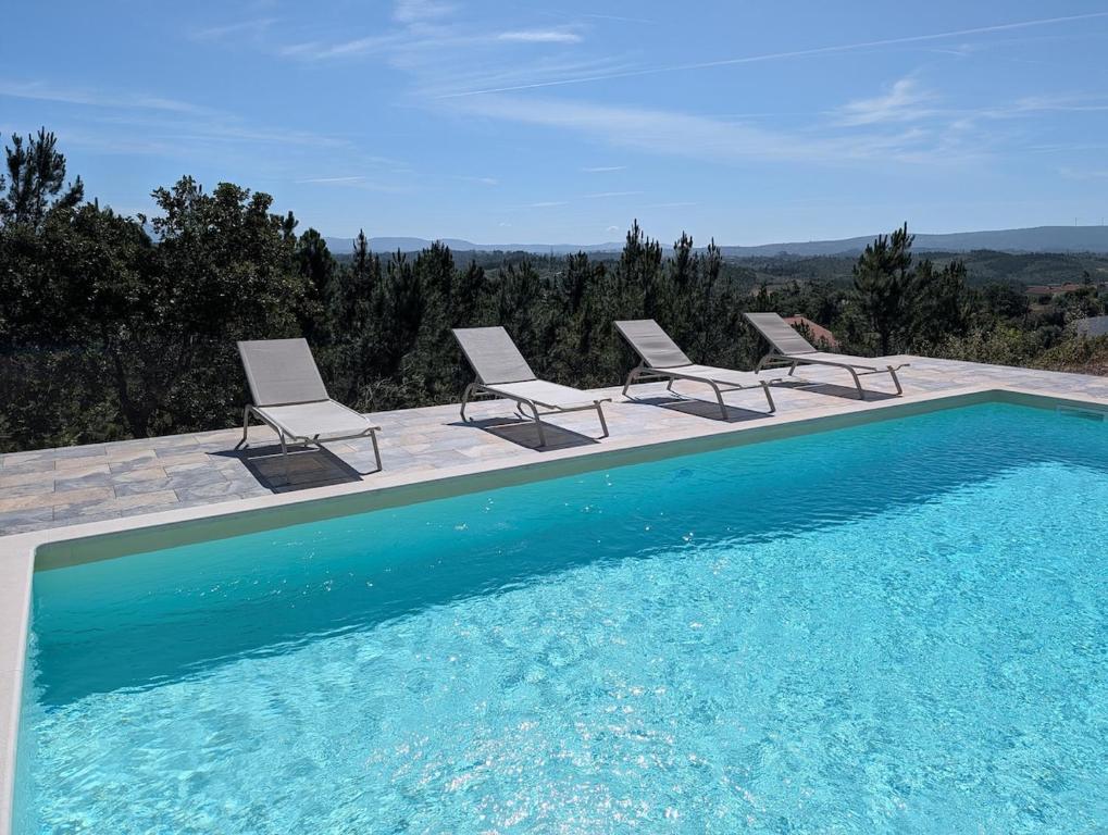 a swimming pool with two chairs and a swimming pool at Casa na Colina - Private Pool & Jacuzzi in Santiago da Guarda