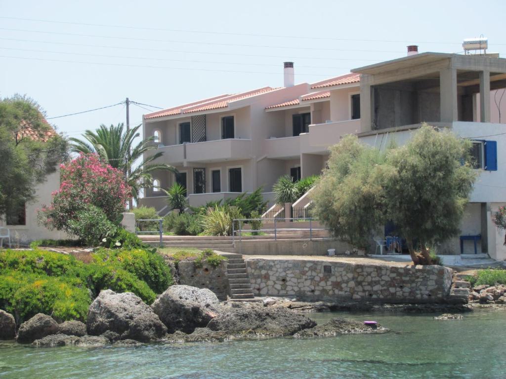 a house next to the water with a building at Lakonia Bay Apartments in Archangelos