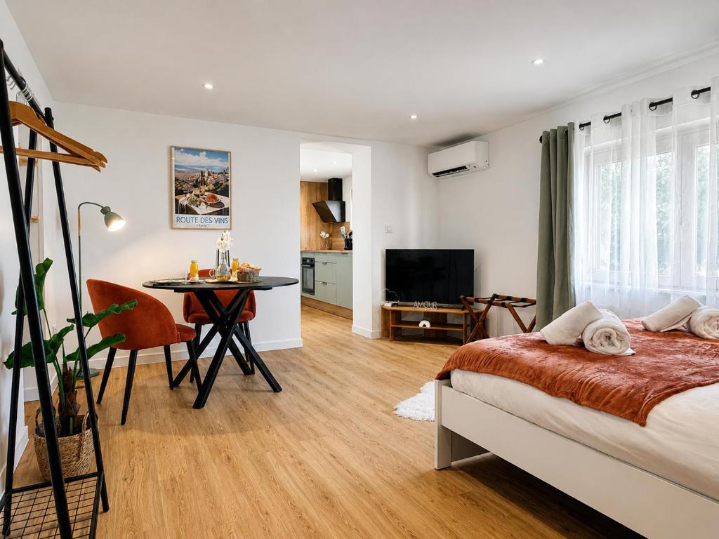 a bedroom with a bed and a table and a television at Entre Terre et Vignes - Studio climatisé in Marlenheim
