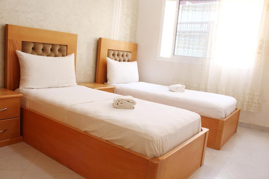 a bedroom with two beds with white sheets and a window at Apart al hoceima in Al Hoceïma