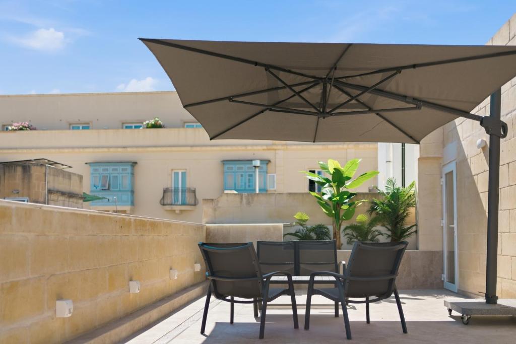 a table and chairs under an umbrella on a balcony at Casa Lina Suites in Sliema