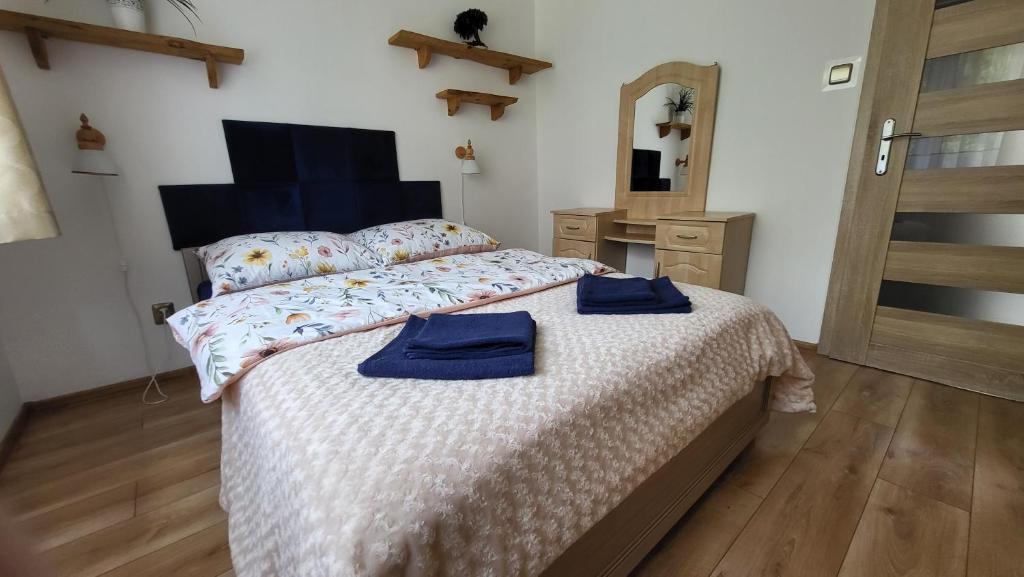 a bedroom with a bed with two blue towels on it at Apartament nad Soliną in Polańczyk
