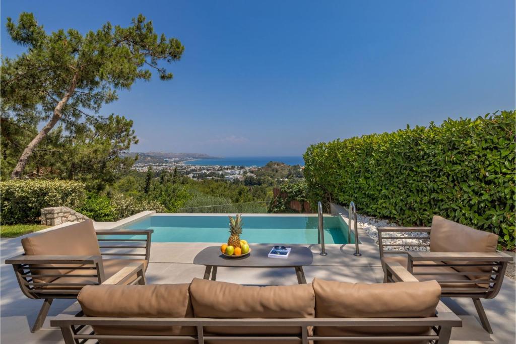 a patio with a table and chairs next to a pool at Aegean View Estate - Villa in Faliraki