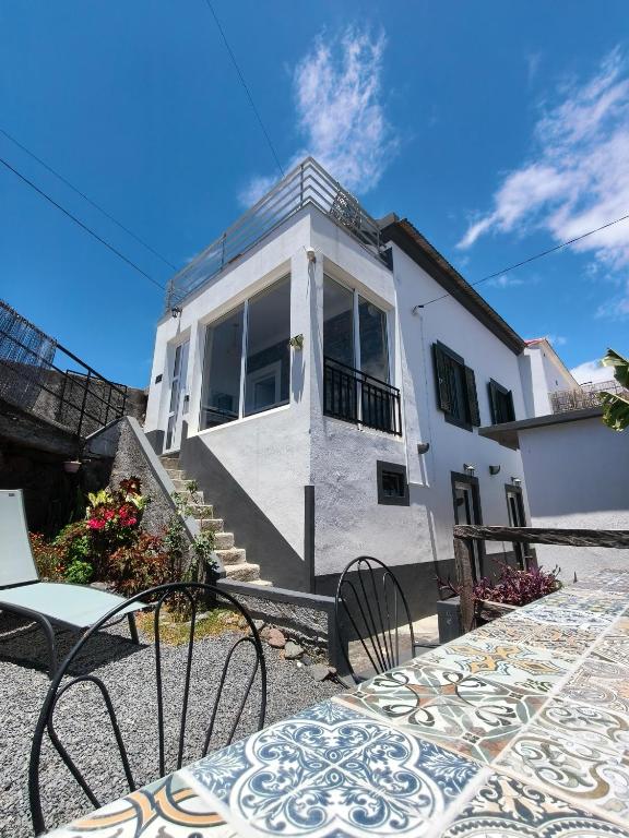 a white house with some chairs in front of it at Isabela House in Ponta do Sol