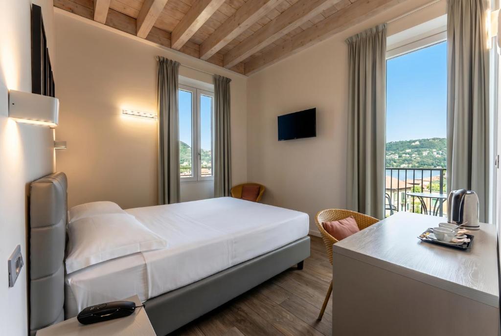 a bedroom with a bed and a desk and a window at Hotel Quarcino in Como
