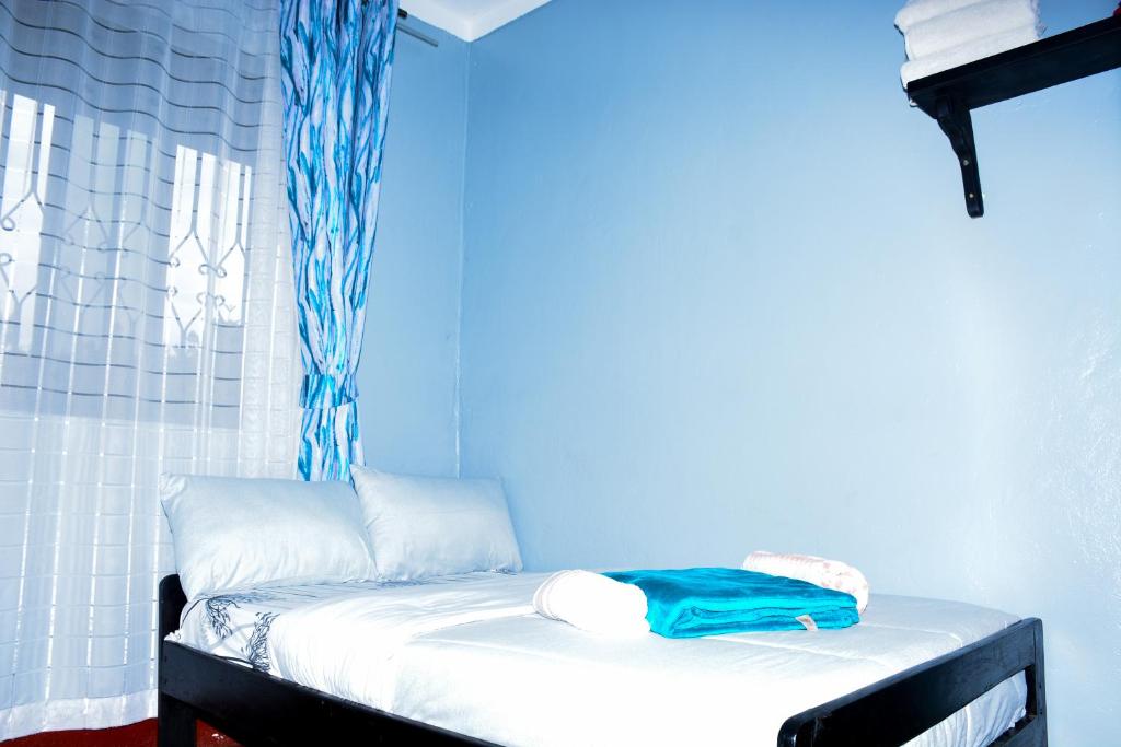 a room with a bed with a blue wall at Larry Homestay in Kapchorwa