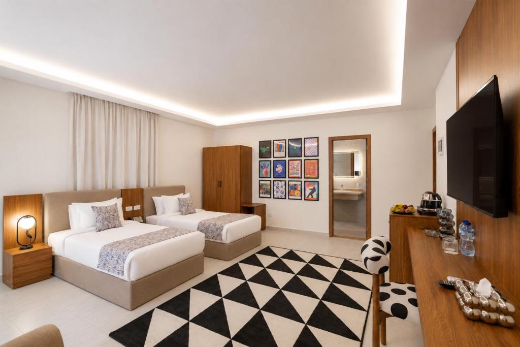 a hotel room with two beds and a flat screen tv at Seven Stays Centric West Zayed in Sheikh Zayed