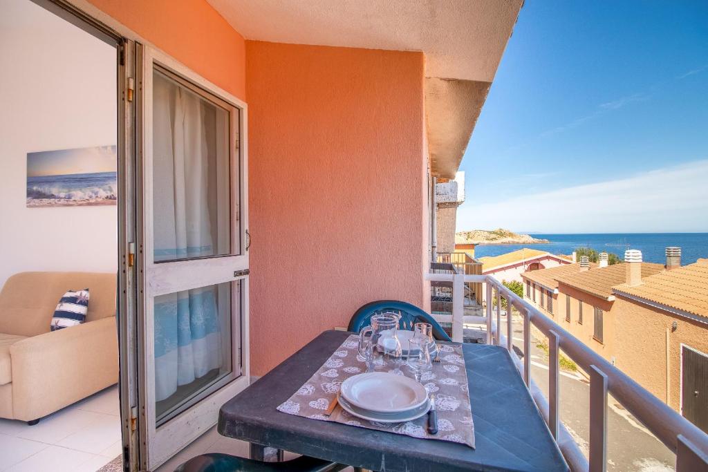 a table on a balcony with a view of the ocean at Vista Corsica in Isola Rossa