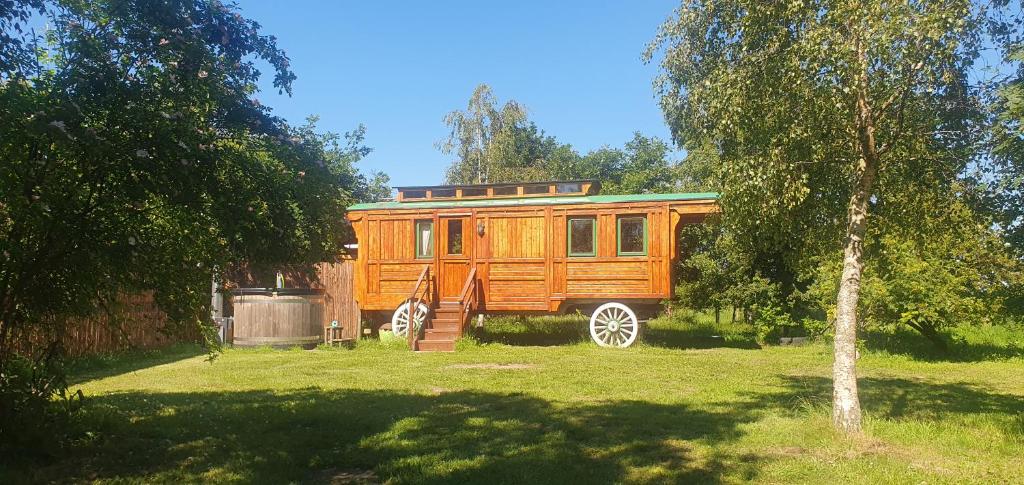 a wooden trailer parked in a field with a tree at The Loft Glamping & Camping in Kinloss