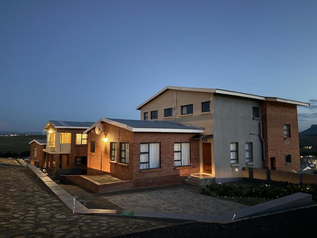 a large brick house in a parking lot at night at Kairos Guest House in Maseru