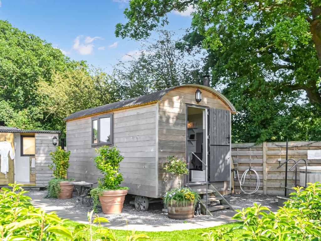 a tiny house in a garden with potted plants at Morning Mist in Strensall