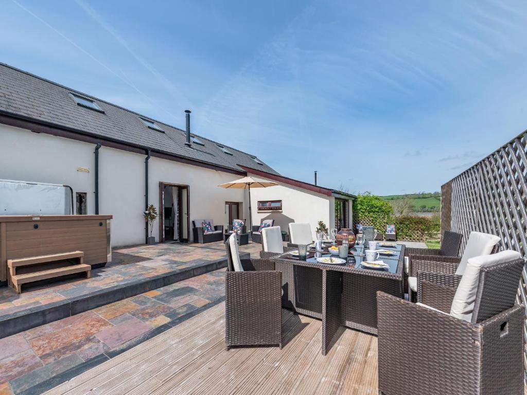 a patio with a table and chairs on a deck at Wheelwright Barn in Llangain