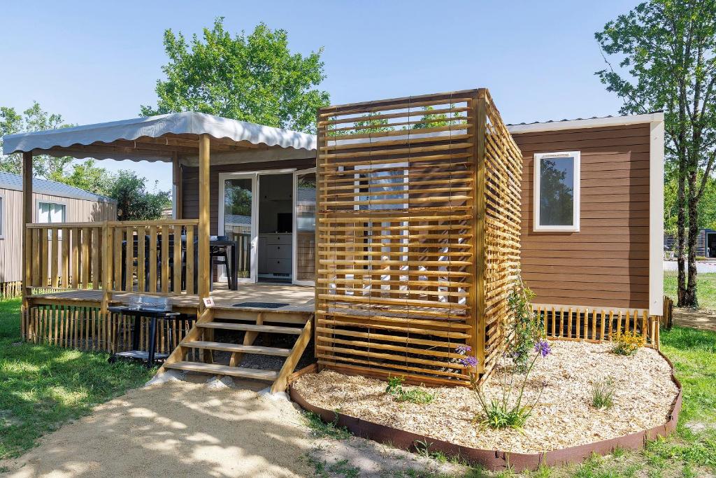 a tiny house with a porch and a deck at Mobilehome Vallon 53 in Saint-Gervais