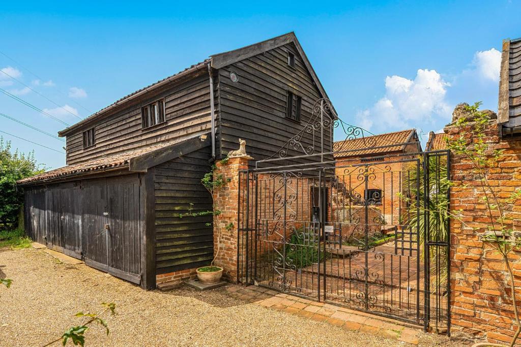 a black house with a gate and a brick building at Barn Conversion Sleeps 2 with Parking in Diss