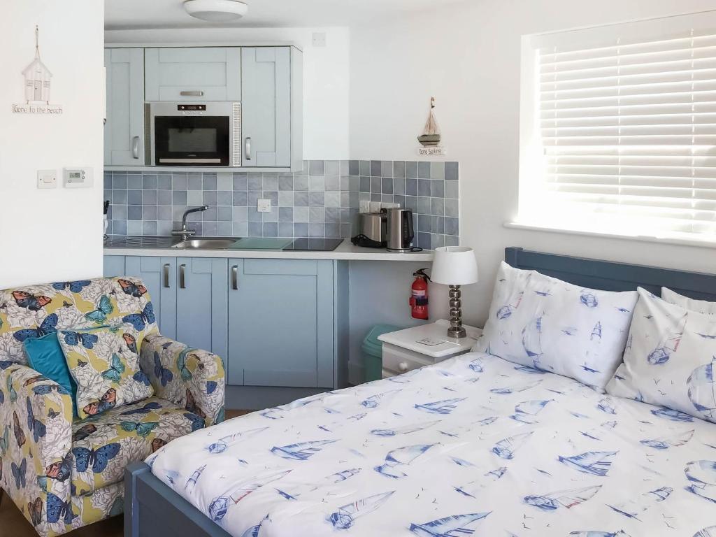a bedroom with a bed and a couch and a kitchen at Farthings - 19292 in Bridport