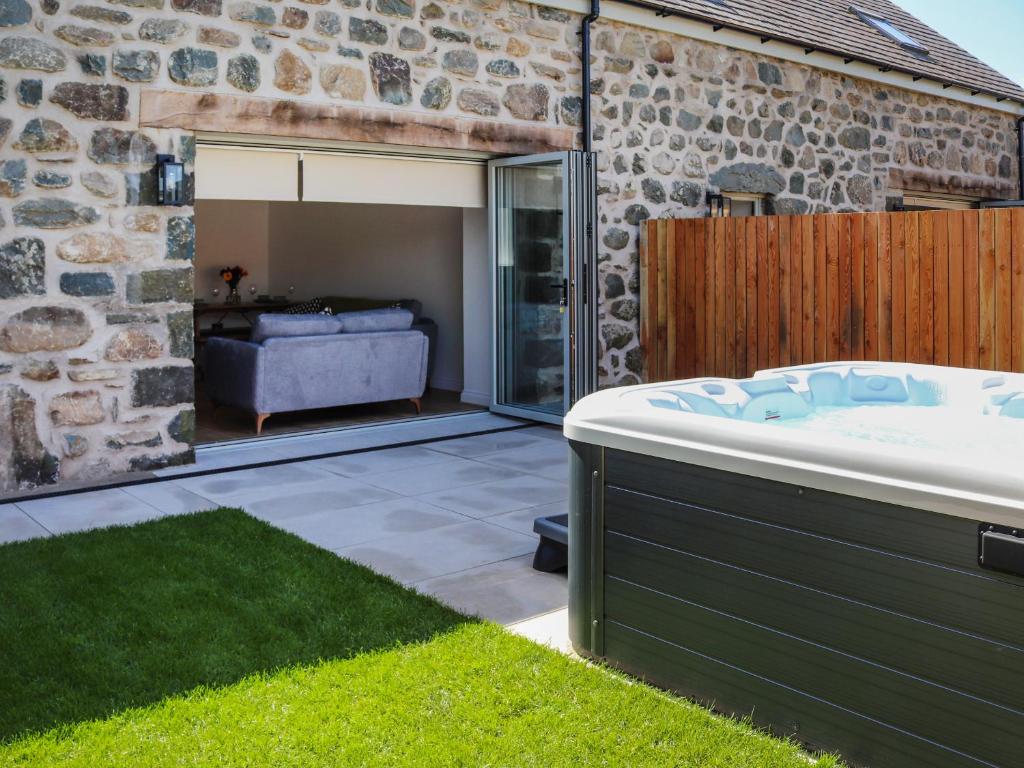 a bath tub in a garden next to a stone building at Bodlyn - Uk48861 in Llanddwywe
