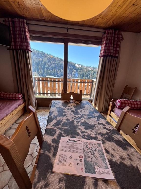 a room with a table and a view of a balcony at Studio Croix Viallet, Chez Francine in Notre-Dame-de-Bellecombe